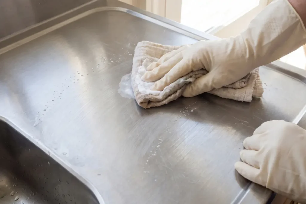 Cleaning stainless steel sink with baking soda following the grain